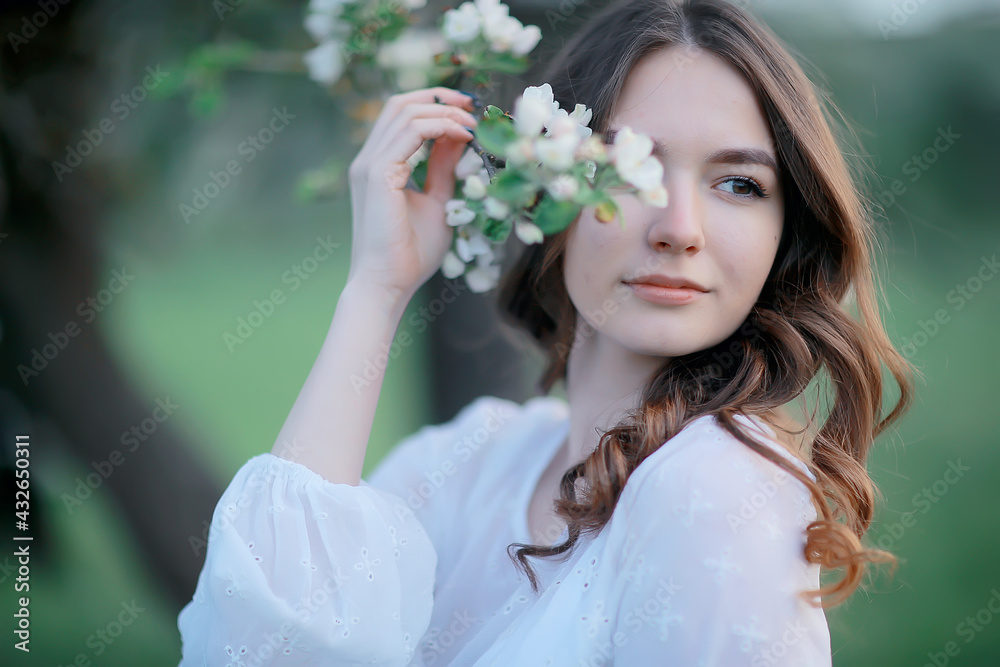 Obraz premium springtime fashion portrait of a young girl in a blooming cherry garden, tenderness of the morning