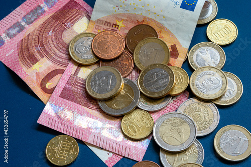 Mehrere Euro Banknoten und Euro Münzen,durcheinander liegend, auf blauen Untergrund