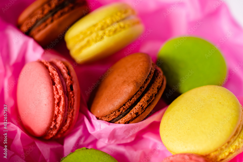 multicolored macarons cakes on a pink paper background multicolored macarons cakes on a pink paper background