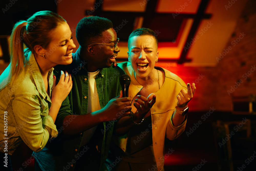 Happy friends singing and having fun while gathering on a night party at the bar. Happy friends singing and having fun while gathering on a night party at the bar.