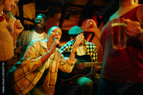 Happy African American woman signing during a night party at the pub.