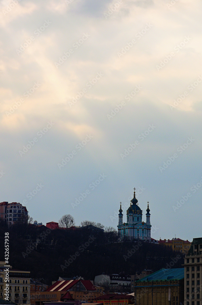Picturesque sunset cityscape view of Kyiv. Ancient Saint Andrew Church on the top of the hill. It is famous travel destination in the city. Colorful buildings of Podil district. Kyiv, Ukraine