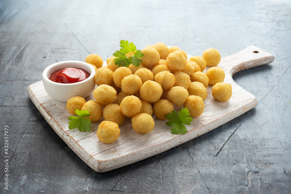 Crispy potato balls with ketchup on white wooden board Crispy potato balls with ketchup on white wooden board