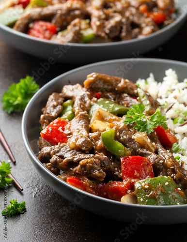 Stir fry Chinese pepper beef steak with onion  red and green bell pepper  rice in bowl