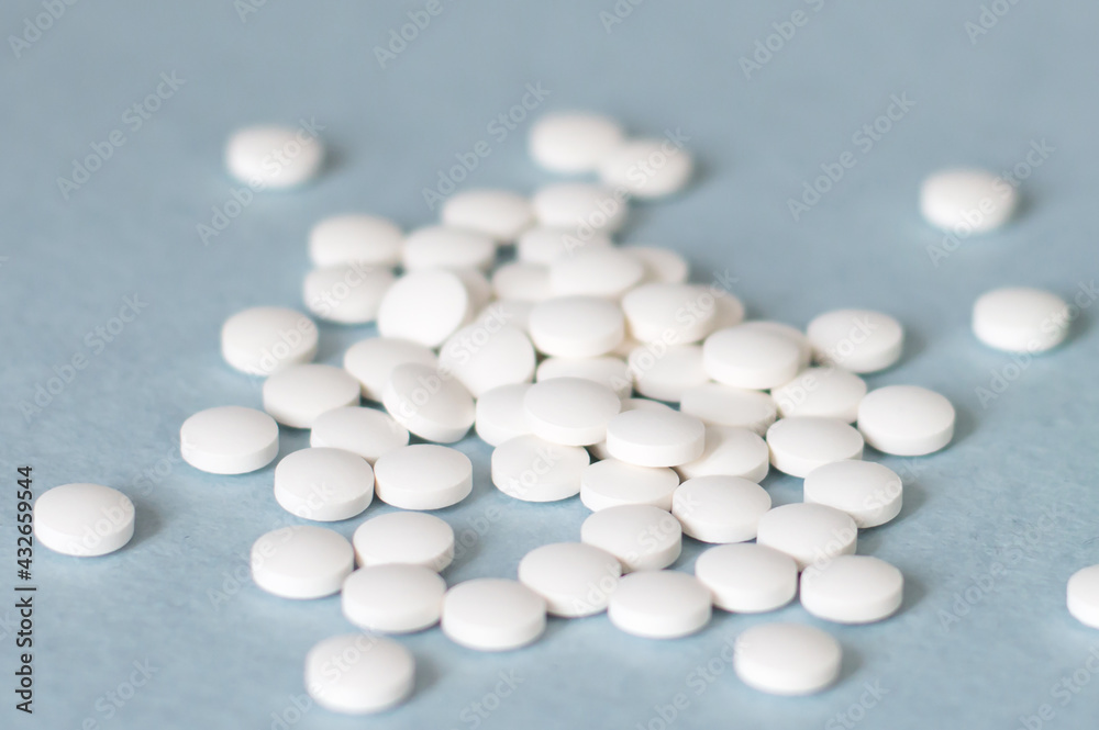 Medication white round tablets arranged isolated on blue background, close-up of tablets. Concept of health, treatment, choice, healthy lifestyle.