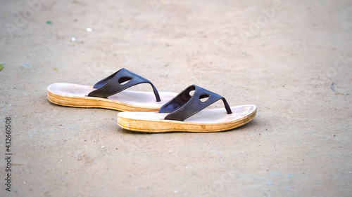 Black and brown Old flip-flop thrown out of the sea over the beach sand.