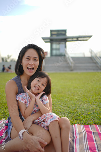 Asian mother and daughter enjoying outdoors picnic