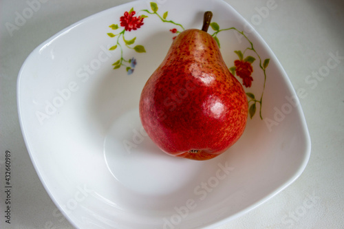 Red pear cut into circles, on a white plate.
