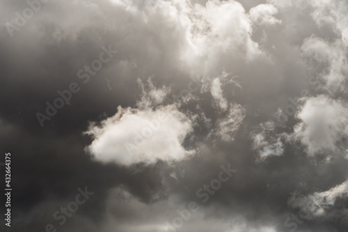 Dramatic sky, sunlit white cloud among dark rain clouds