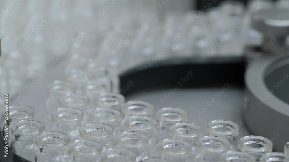 Conveyor belt with empty medical injection glass vials - automatic production line: close up. Manufacturing, medicine and automated pharma technology equipment, pharmaceutical industry concept Conveyor belt with empty medical injection glass vials - automatic production line: close up. Manufacturing, medicine and automated pharma technology equipment, pharmaceutical industry concept