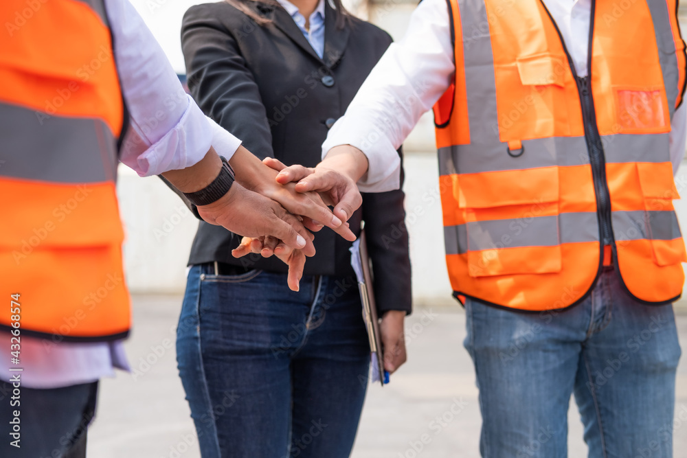 Unidentified group of multi mix race worker with supervisor  holding hand to cheer up and encourage before working at industrial factory site. Teamwork, labor brainstorm or group working concept.