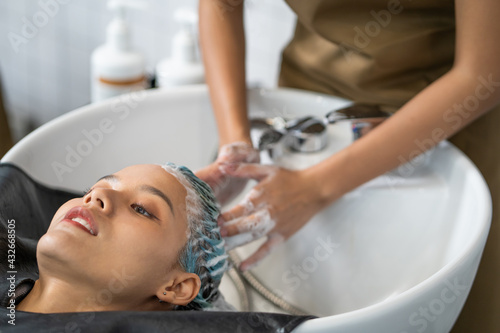 Beautiful Caucasian women feel relax and comfortable while getting hair wash with shampoo and massage. Hair salon studio with hair stylish, beauty and fashion concept.
