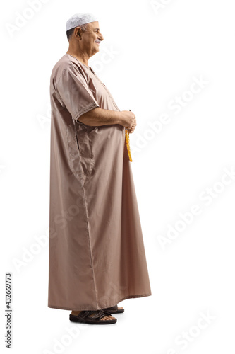 Full length profile shot of a muslim man in traditional clothes