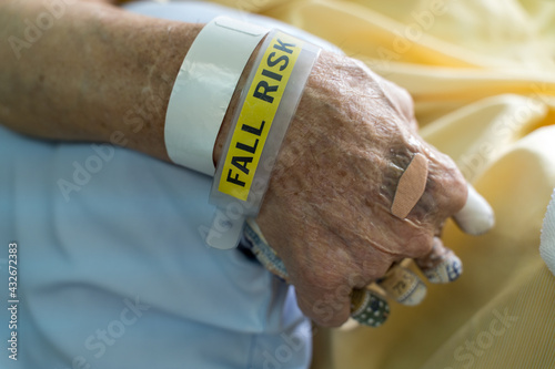Obraz na płótnie A hospital patient wearing a fall risk bracelet and fingers separation pad anti-bedsore elder bedridden patients in the patient's hand. w salonie