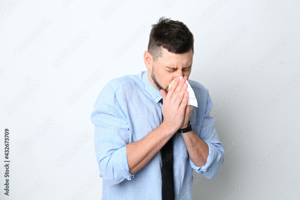 Man with tissue suffering from runny nose on white background Man with tissue suffering from runny nose on white background