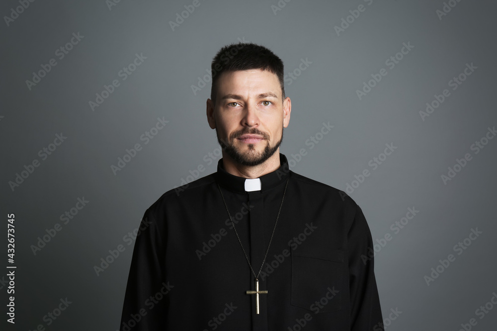 Obraz premium Priest wearing cassock with clerical collar on grey background