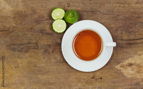 Bergamot tea or Earl Grey tea in white cup and fresh bergamot fruit with sliced on brown wooden table, top view.