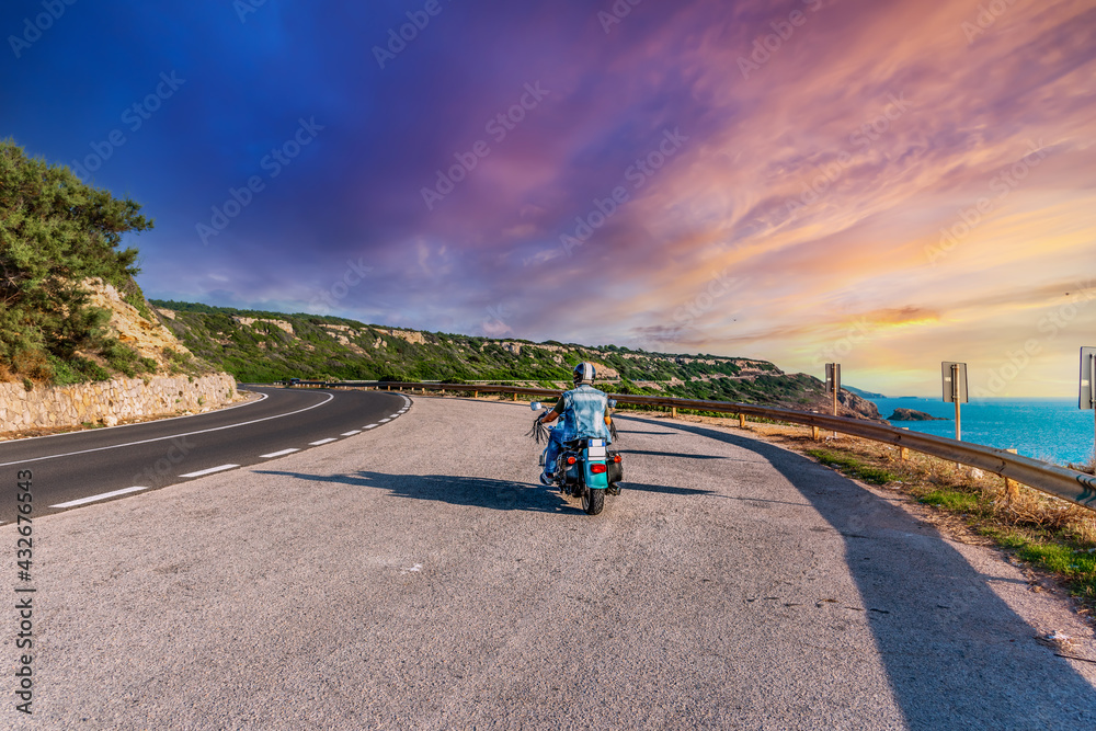Obraz premium Biker on a winding road under a pink sky
