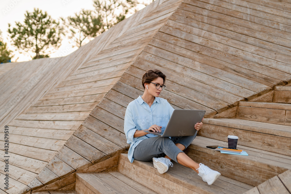 young pretty woman working on laptop in modern park street young pretty woman working on laptop in modern park street