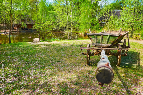 The old cart, lake and timber hata house, Mamajeva Sloboda Cossack Village, Kyiv, Ukraine photo