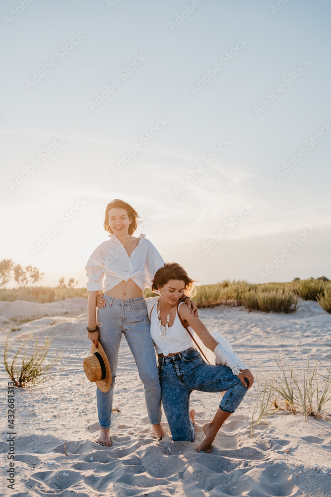 two young women having fun on the sunset beach