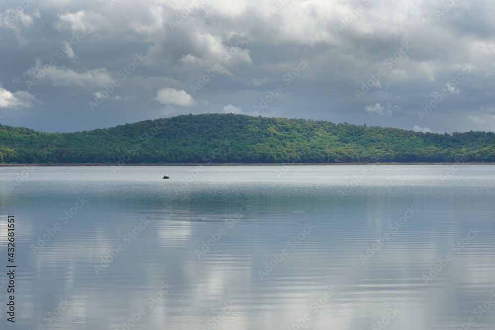 boat with passengers in distance under heavy colds in a calm lake boat with passengers in distance under heavy colds in a calm lake