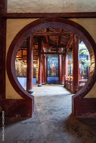 Fengdu, China - May 8, 2010: Ghost City, historic sanctuary. Circular door opening to Buddhist sanctuary with golden statues behind glass windows. photo
