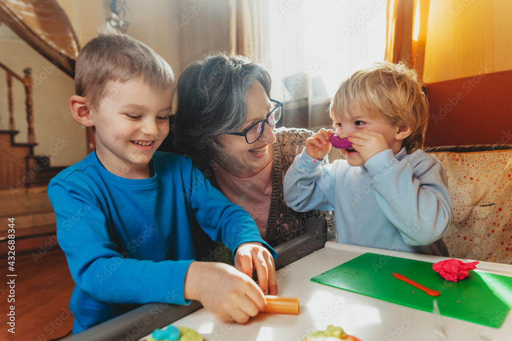 Fototapeta premium Grandmother playing with her grandchildren with kids play clay