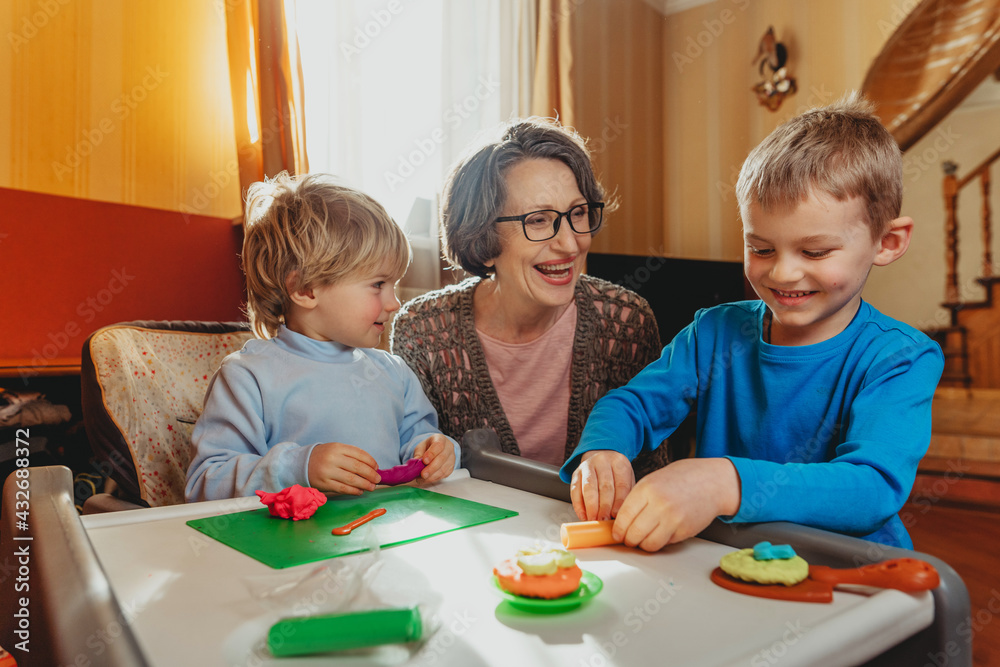 Grandmother playing with her grandchildren with kids play clay Grandmother playing with her grandchildren with kids play clay