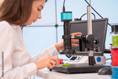 Young female designer working on a prototype device on a 3D printer