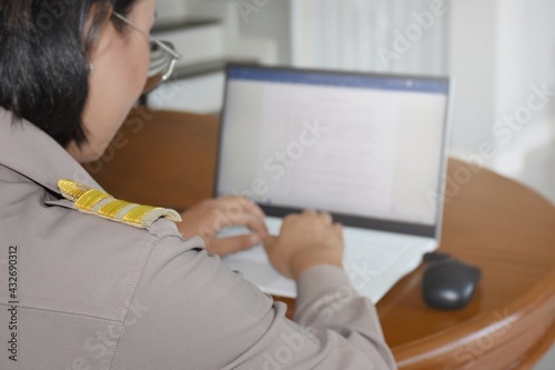 Thai teachers in Thai government uniforms are working on a computer