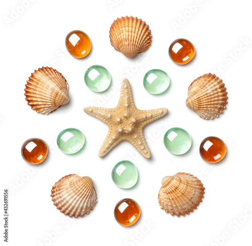 Pattern in the form of a circle made of shells, starfish and green and yellow glass beads isolated on white background