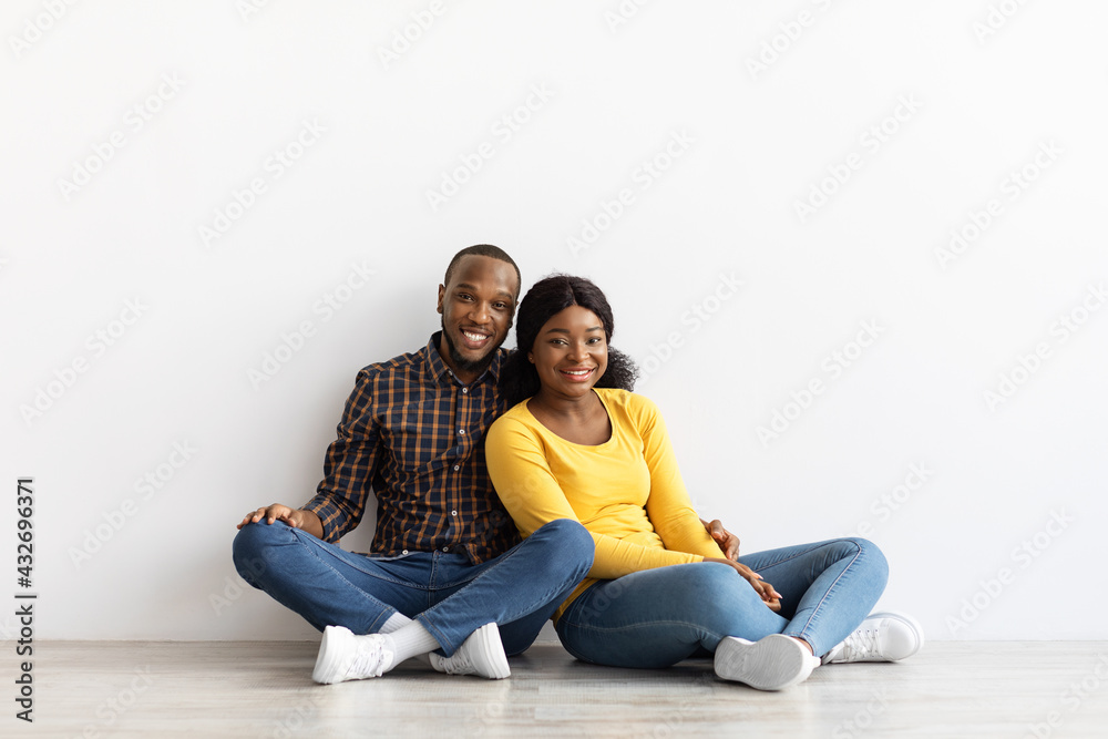 Portrait Of Happy Black Couple Sitting On Floor In Empty Flat