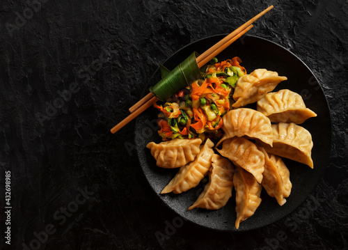 Asian Gyoza dumplings with pork meat and vegetables on a black background. Top view photo