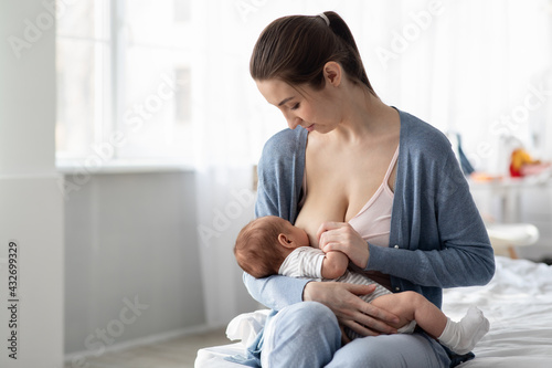 Portrait Of Young Beautiful Woman Breastfeeding Her Infant Child At Home photo