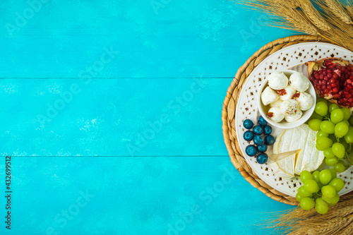 Jewish holiday Shavuot celebration concept with cheese,  wheat ears and fruits on wooden blue table background photo