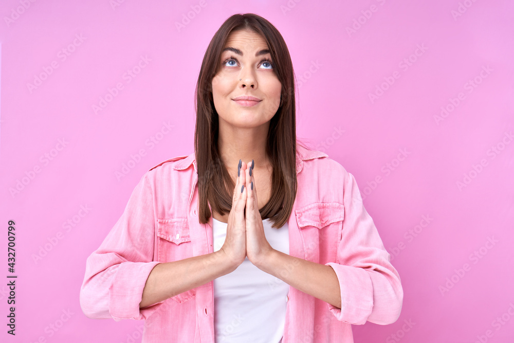 Portrait of brunette girl in prayer pose smiling and looking up, asks forgiveness and hopes for help isolated on pink studio background Portrait of brunette girl in prayer pose smiling and looking up, asks forgiveness and hopes for help isolated on pink studio background
