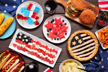 Fourth of July, patriotic, American themed food. Overhead view table scene on a dark wood background.