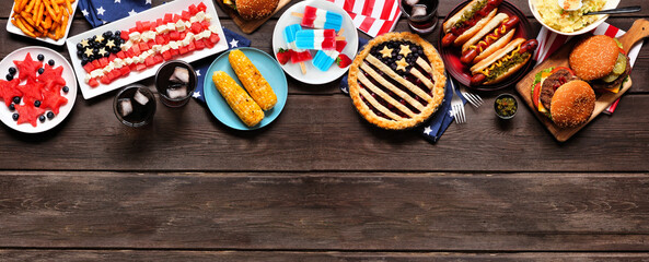 Fourth of July, patriotic, American themed food. Overhead view top border on a dark wood banner background. Copy space.