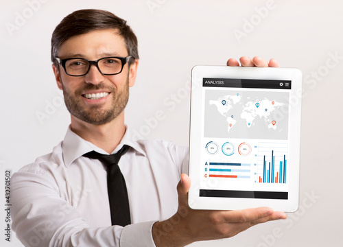 Happy businessman holding digital tablet with financial app on screen