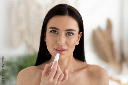 Obraz na plátně Pretty woman using hygienic lipstick balsam