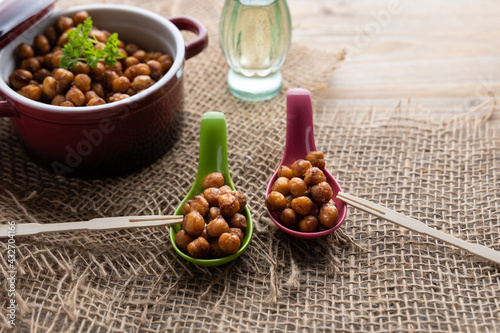 Vegan grilled chickpeas. Homemade vegan chickpeas, Crispy roasted organic chickpeas . Served as a snack in a bowl, on a wooden table top.