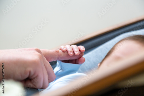 Peaceful and sleepy newborn baby, focus on the hand; family and love theme photography