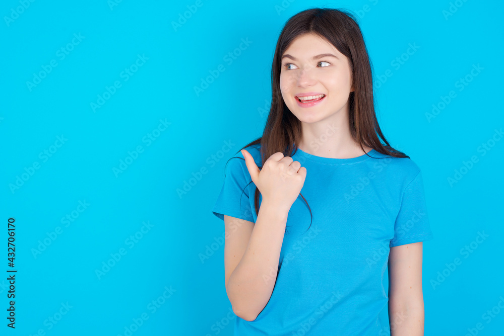 young beautiful Caucasian woman wearing blue T-shirt over blue wall points away and gives advice demonstrates advertisement young beautiful Caucasian woman wearing blue T-shirt over blue wall points away and gives advice demonstrates advertisement