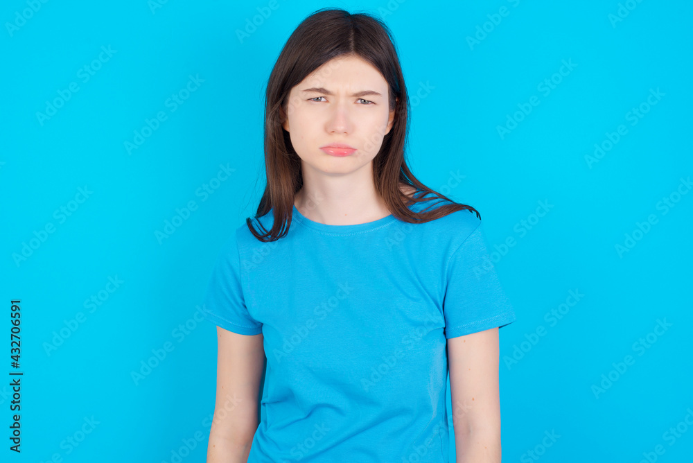 young beautiful Caucasian woman wearing blue T-shirt over blue wall depressed and worry for distress, crying angry and afraid. Sad expression. young beautiful Caucasian woman wearing blue T-shirt over blue wall depressed and worry for distress, crying angry and afraid. Sad expression.