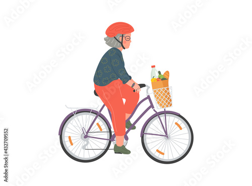 Senior woman cycles on bicycle with basket. Elderly woman in helmet with grocery bag on bike.