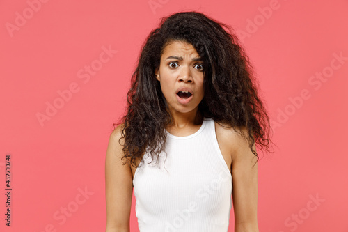 Young shocked confused amazed, astonished surprised african american woman 20s in casual white tank shirt looking camera with opened mouth isolated on pink color background. People lifestyle concept
