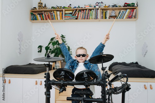 Little boy superstar in sunglasses playing electronic drums at home photo