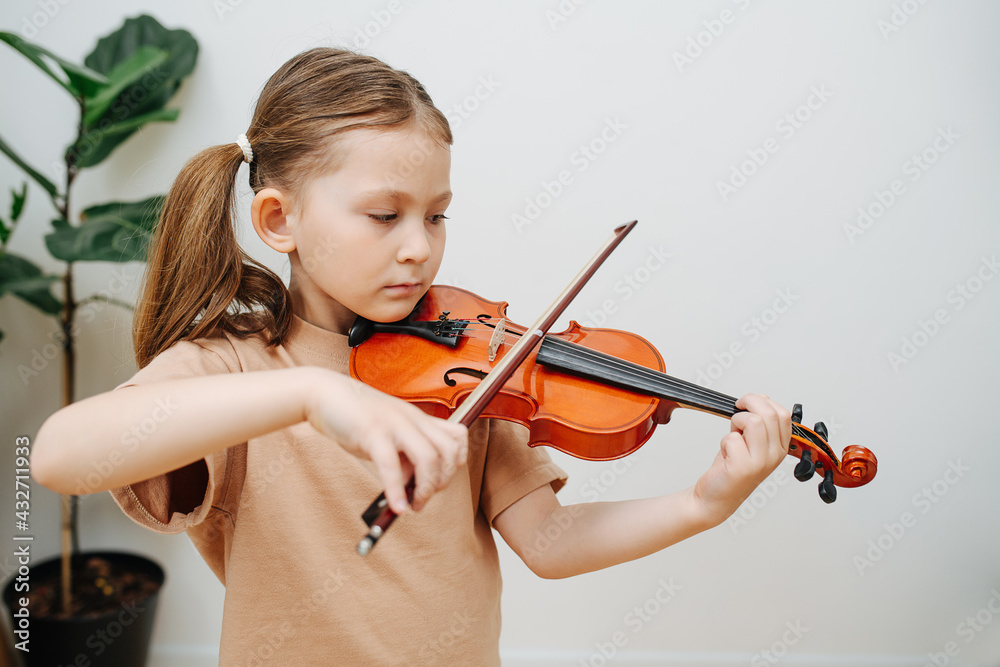 Determined little girl learning to play violin, focusing on her fingers pressing Determined little girl learning to play violin, focusing on her fingers pressing