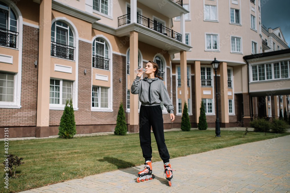 Young girl rides roller skates and drinks clean water